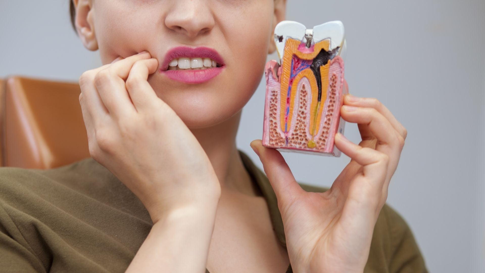 A woman holding tooth decayed model